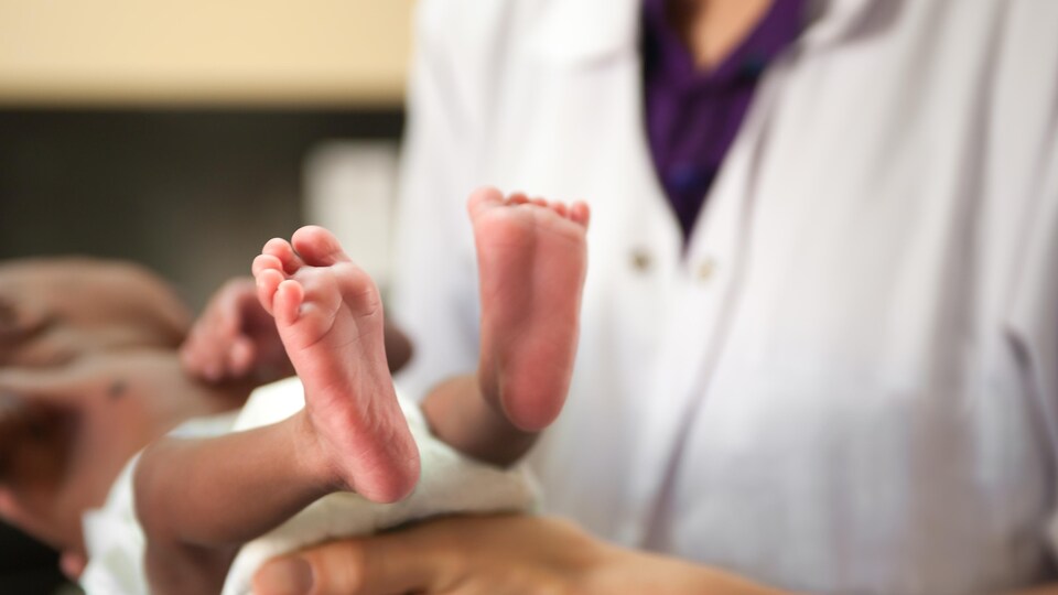 Un professionnel de la santé tient dans ses bras un bébé.