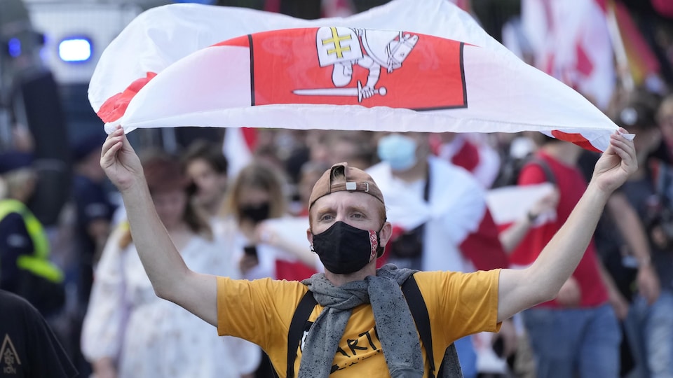 Un joven ondea la bandera bielorrusa durante una manifestación en Polonia.