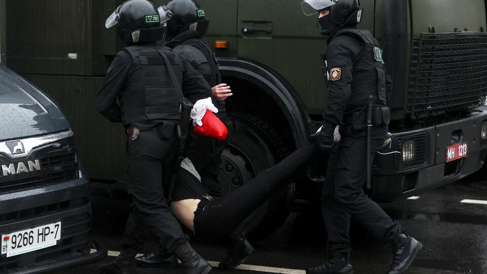 Trois policiers portent un manifestant par les jambes et les bras. 