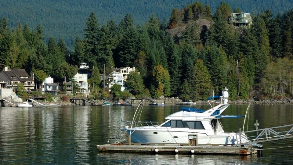 Des maisons en arrière-plan autour d'un lac et en avant-plan un bateau à quai.