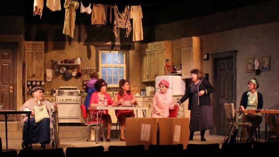 Neuf actrices, toutes blanches, jouent une scène de la pièce de théâtre Les Belles Soeurs.