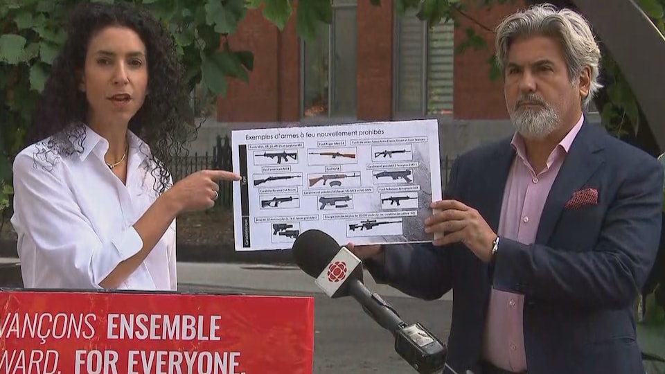 Rachel Bendayan pointe une affiche tenue par Pablo Rodriguez et qui montre différentes armes à feu et Pablo Rodriguez lors d'un point de presse.