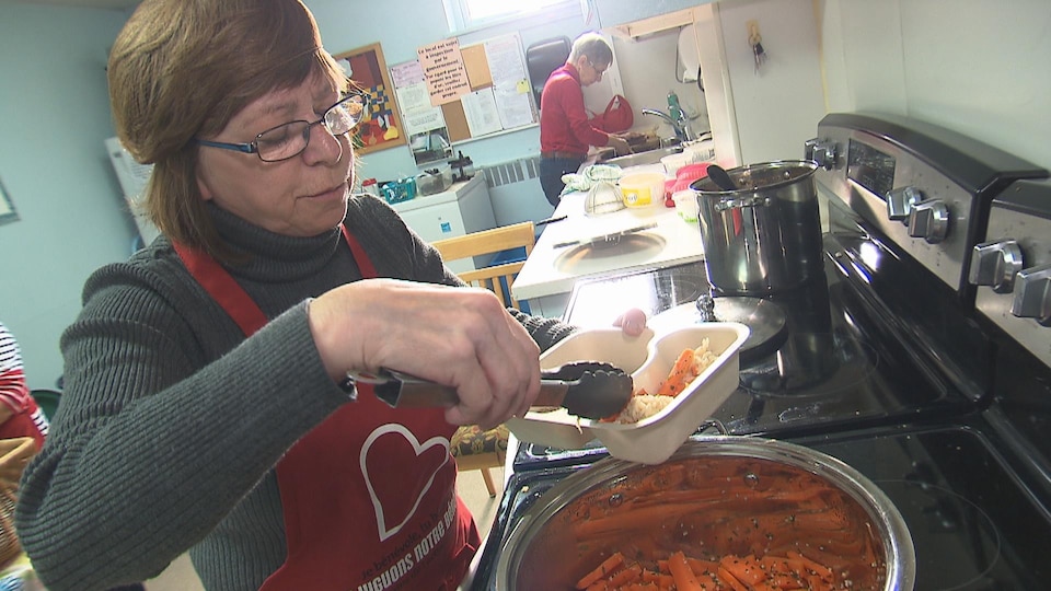 Des bénévoles dans une cuisine collective préparent des repas.