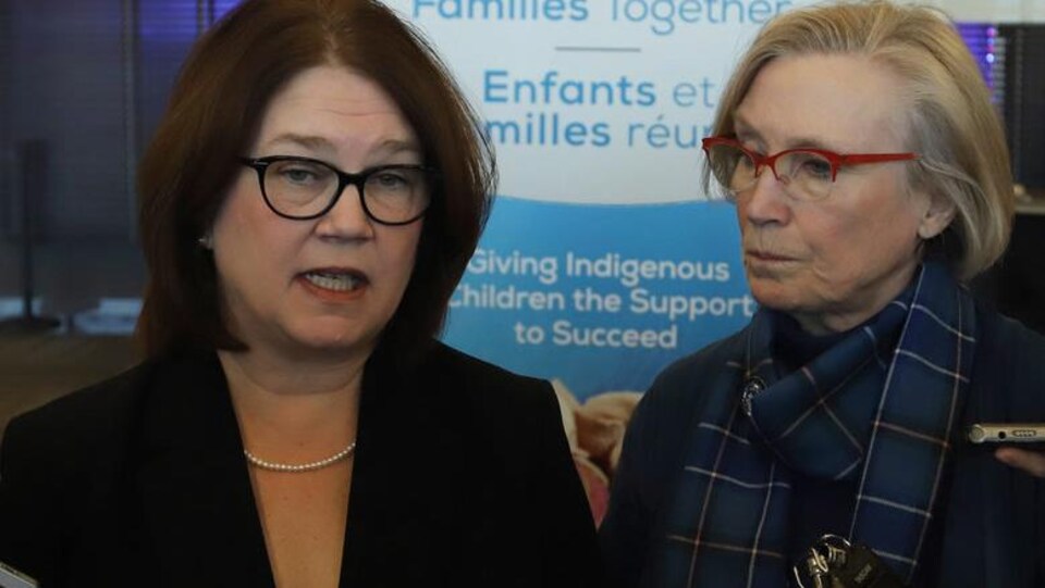 Deux femmes avec des lunettes répondent aux questions des journalistes.