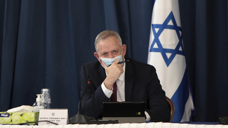Le ministre israélien de la Défense Benny Gantz, assis à une table devant un drapeau de l'État hébreu.