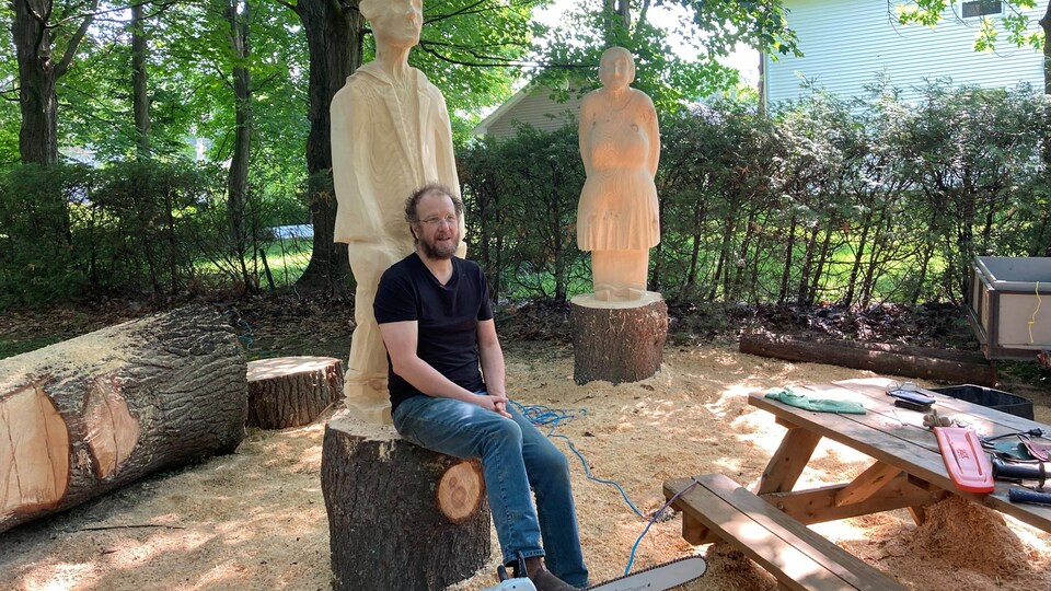 Un homme devant des sculptures.