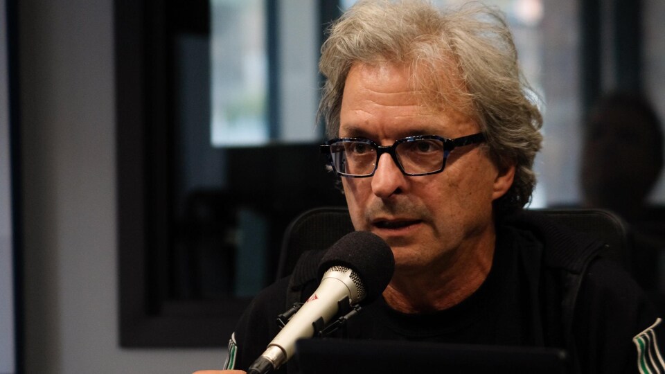 Un homme avec des lunettes rectangulaires dans un studio de radio.