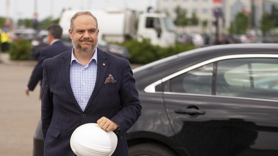 M. Dorais devant une voiture, un casque de construction à la main.