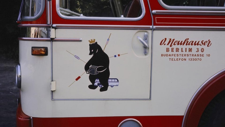 Un ours aux couleurs des divisions de la ville de Berlin sur un autocar qui circule dans la ville en 1965.