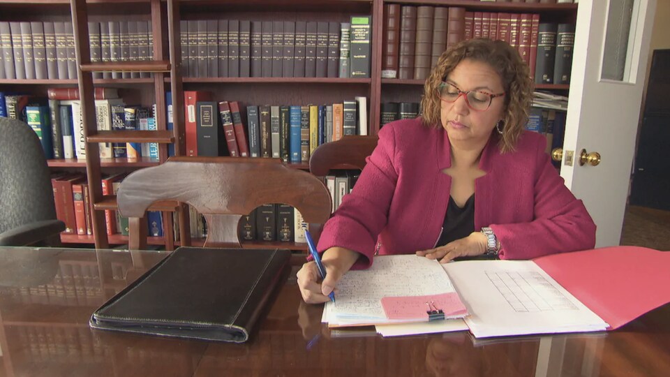Bernadette Clément, la mairesse de Cornwall signe des papiers assise à une table.