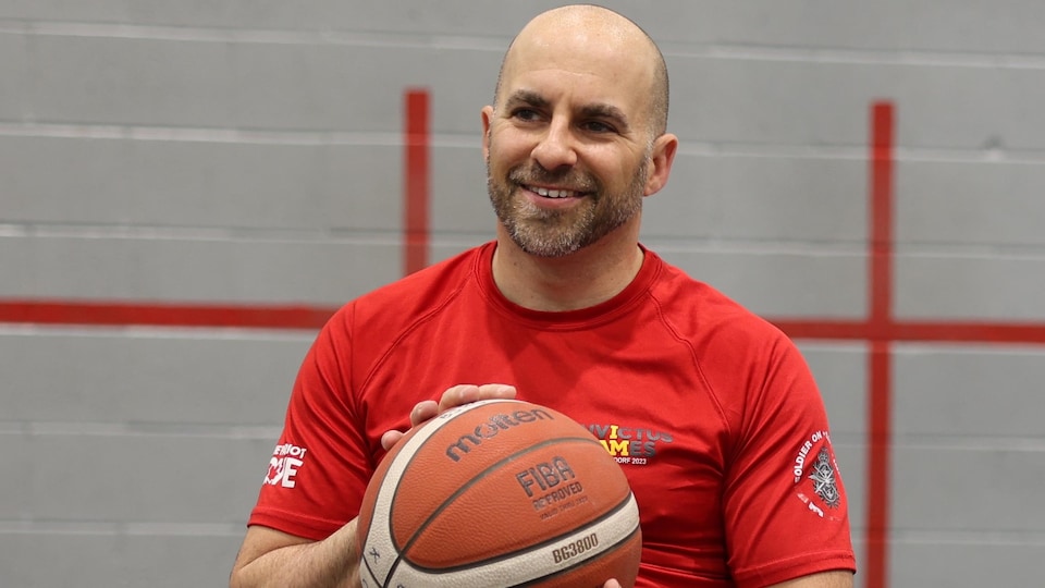 Un homme en fauteuil roulant, tenant un ballon de basketball.