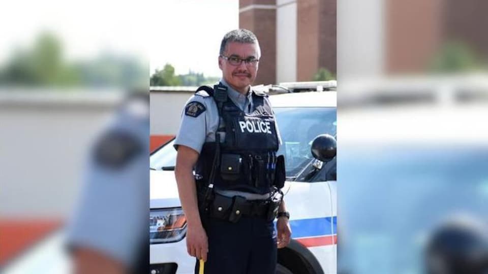 Bernie Herman, en uniforme de la GRC, est debout près d'une voiture de police.