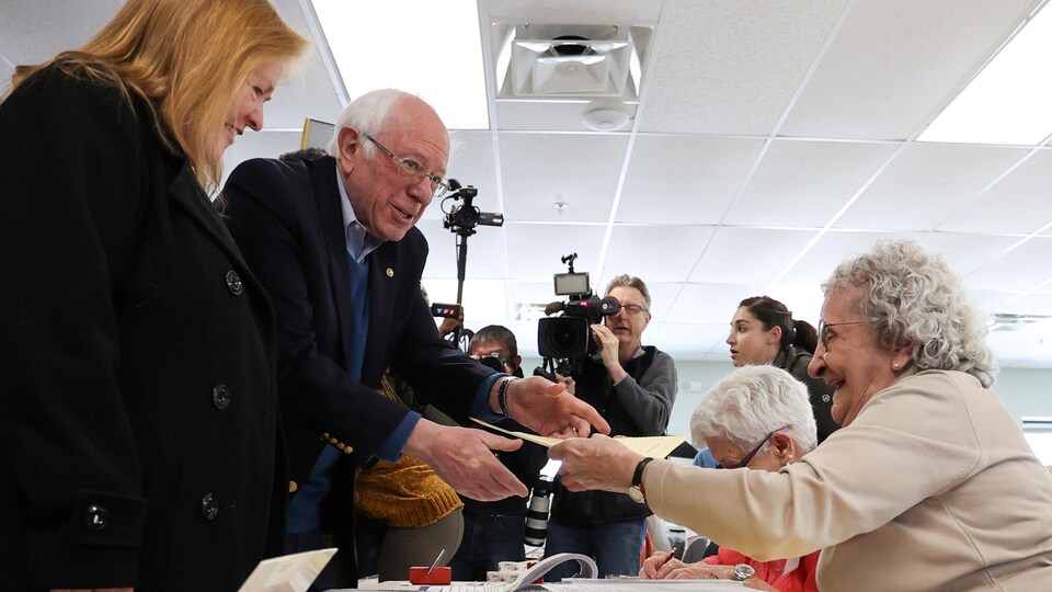 Bernie Sanders et sa femme se font donner leur bulletin de vote par une femme âgée.
