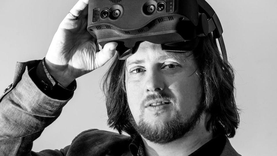 Un homme découvre son visage de son casque de réalité virtuelle. 