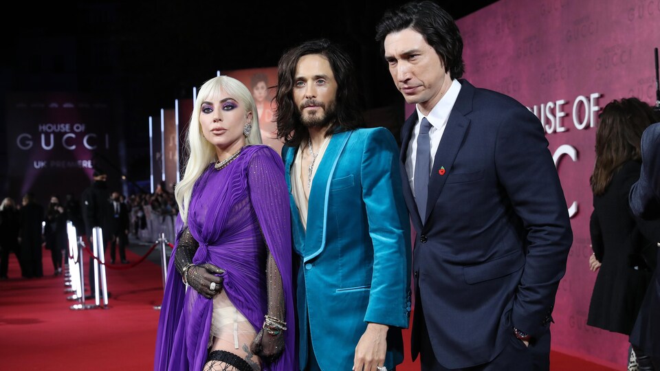 Une femme et deux hommes posent pour les caméras sur le tapis rouge d'un cinéma londonien. 