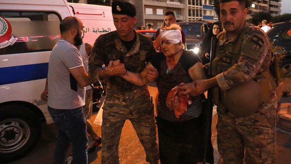 Deux soldats aident une femme blessée à la tête.