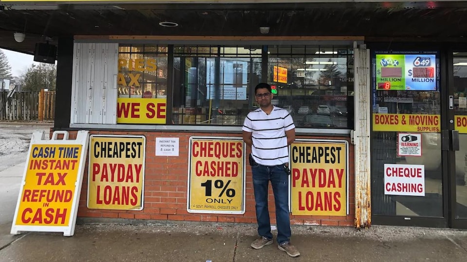 Un homme posant devant un dépanneur.
