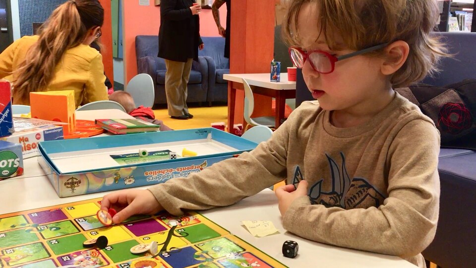 Un enfant portant des lunettes est installé à une table et joue à un jeu.