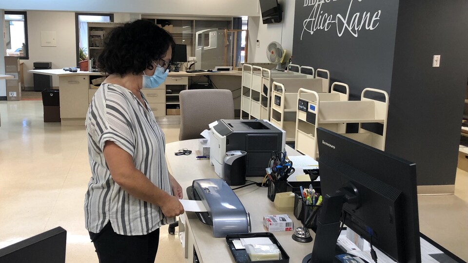 Une dame imprime un passeport vaccinal.
