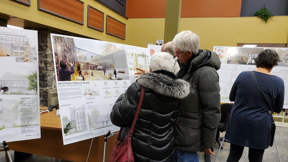Deux personnes observent les esquissent de la future bibliothèque de Rivière-du-Loup.