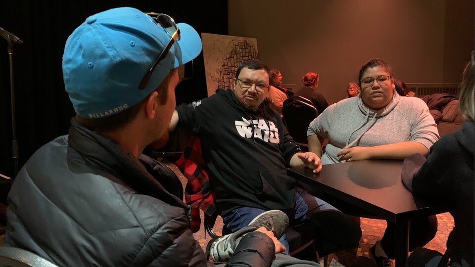 Plusieurs personnes discutent à des tables dans une salle.