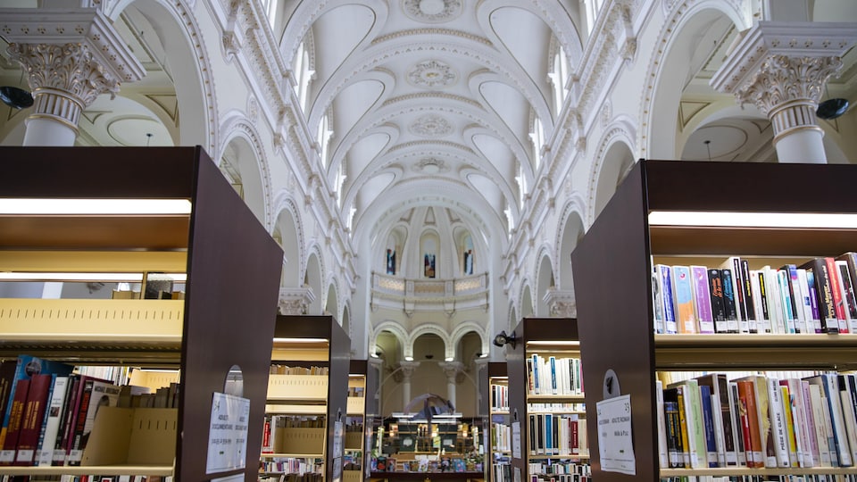Des rangées de livres dans une bibliothèque aménagée à l'intérieur d'une ancienne église.