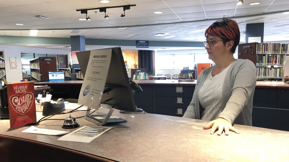Une employé de bibliothèque travaille sur un ordinateur.