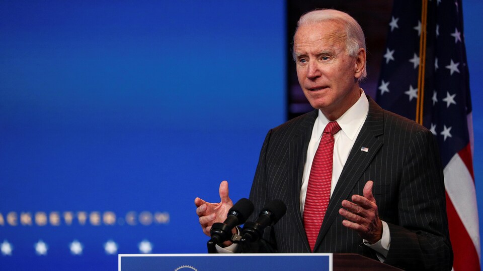 Joe Biden, s'adressant aux reporters, devant un drapeau américain 
