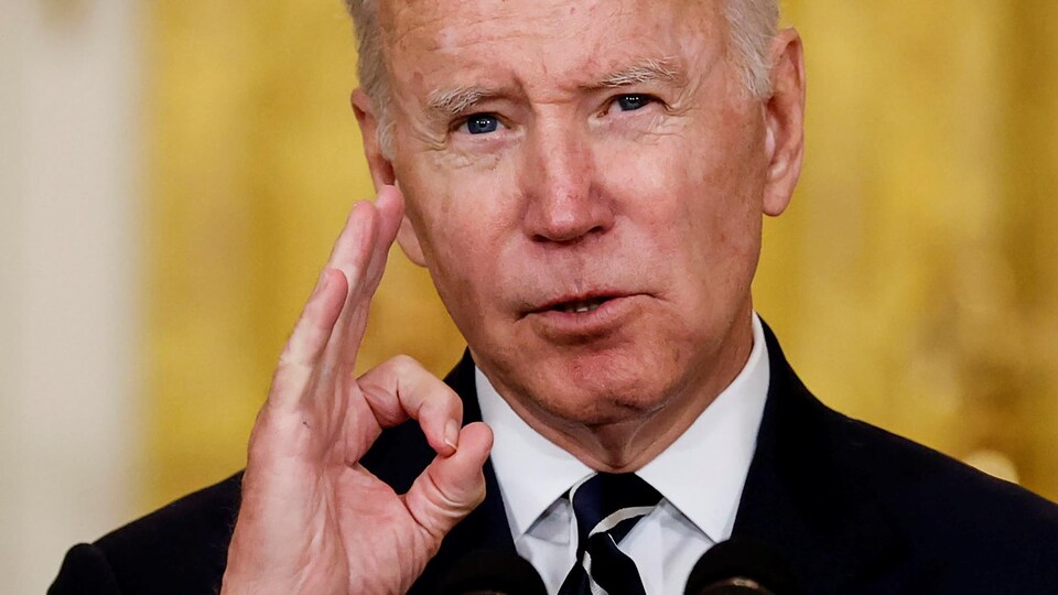 Joe Biden, devant les micros, fait le signe « zéro ».  