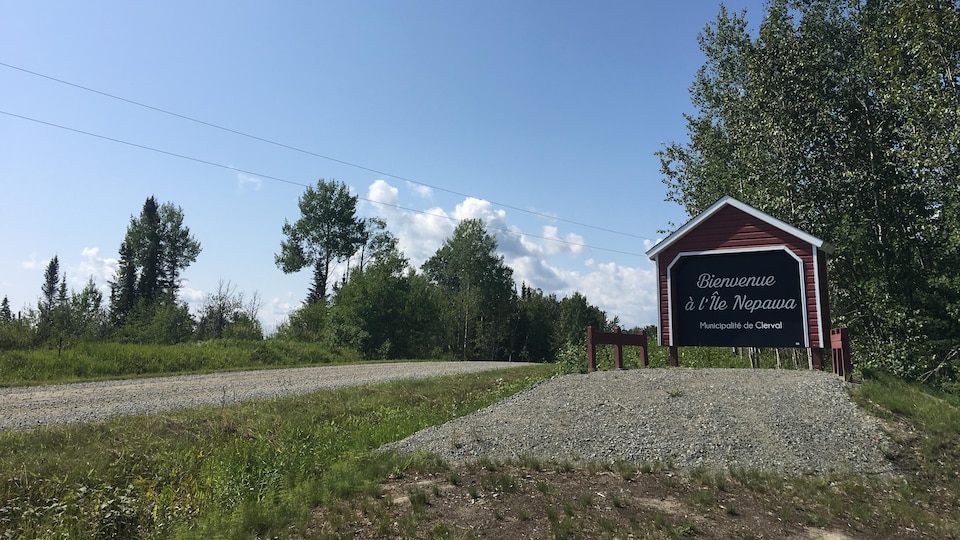 Une affiche en forme de pont couvert indique «Bienvenue à l'Île Nepawa», municipalité de Clerval.