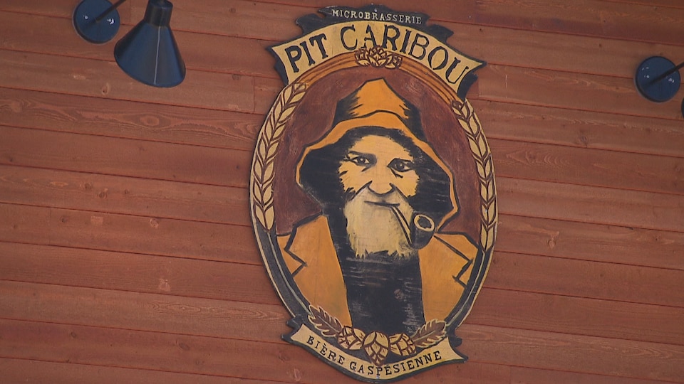 Sur le mur est affiché le logo de la microbrasserie Pit Caribou : bière gaspesienne.