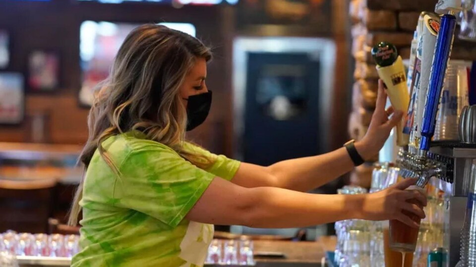 Une serveuse sert une bière dans un bar.