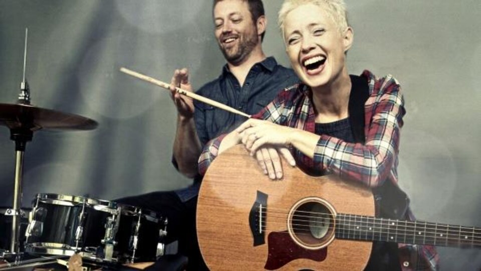 Le batteur et la guitariste du groupe Big Little Lions sont debout devant leurs instruments