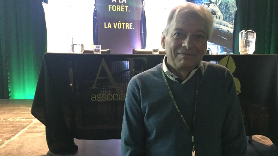 Luc Bouthillier pose devant la scène de la conférence. 