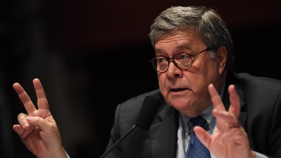 Bill Barr gesticule assis à une table.