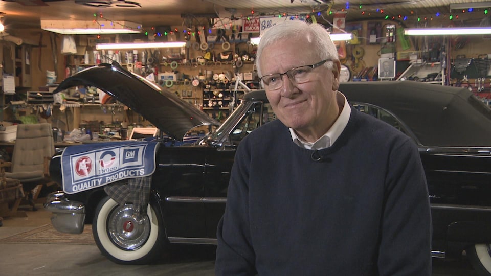 Bill Casey dans son garage devant une voiture de collection.