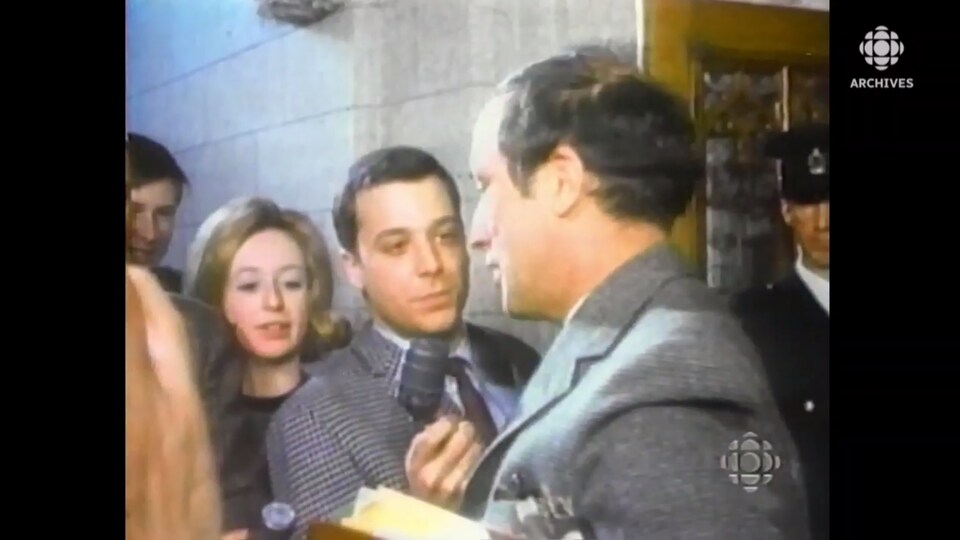 Pierre Elliott Trudeau devant des journalistes qui lui tendent le micro.