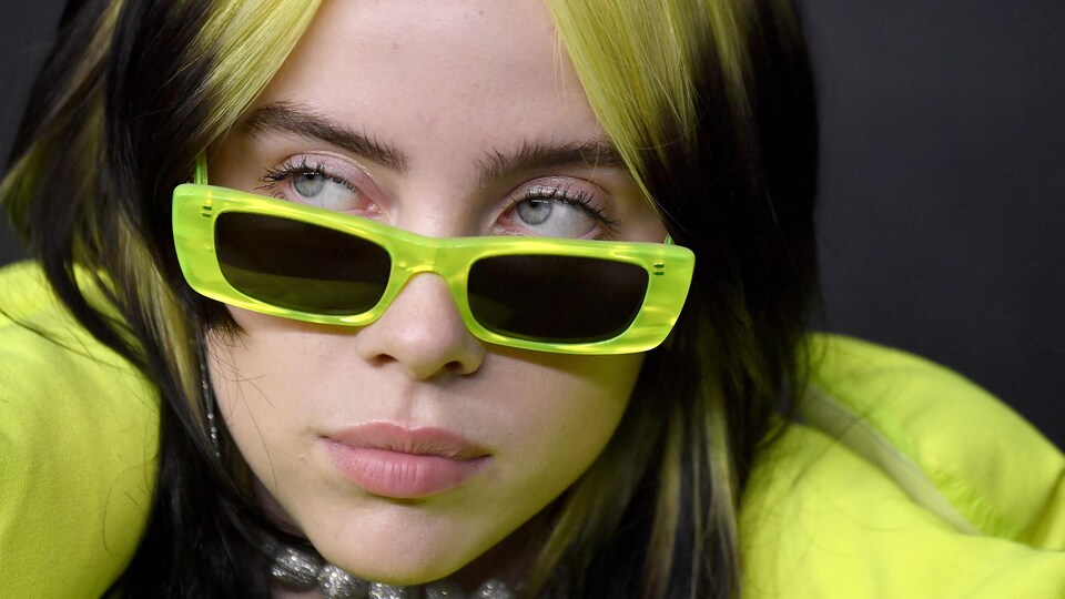 La chanteuse porte des lunettes de soleil vertes.