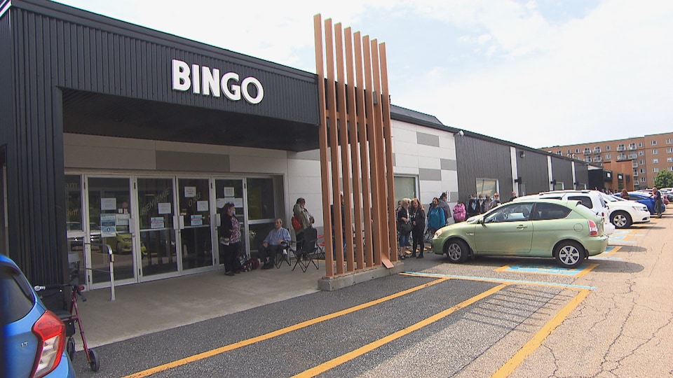 File de personnes devant une salle de bingo en été.