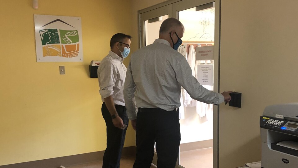 Un membre du personnel place un doigt sur le lecteur biométrique près de la porte d'entrée de la biobanque.
