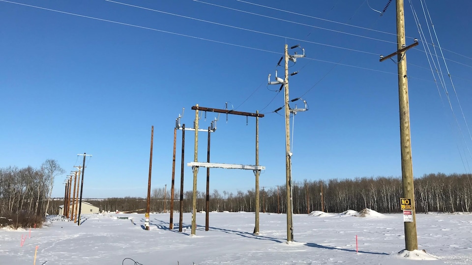 Des poteaux électriques sur un terrain enneigé.