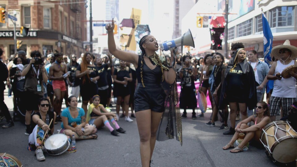 Une femme parle dans un mégaphone au milieu de manifestants lors du défilé de la Fierté.