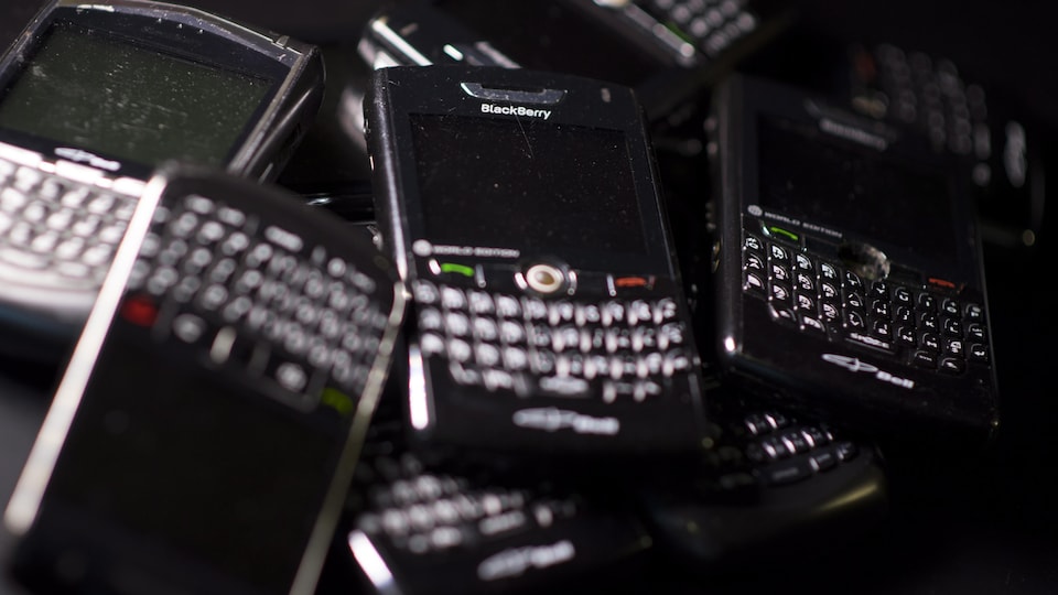 Des vieux téléphones BlackBerry, empilés. 