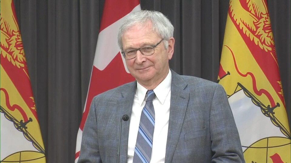 Blaine Higgs entre deux drapeaux du Nouveau-Brunswick.