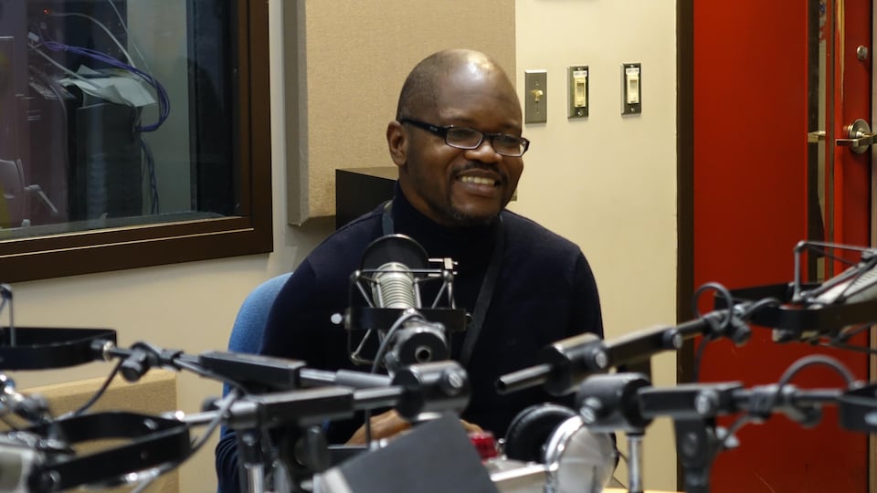 Un homme d'origine congolaise parle au micro dans un studio de radio.