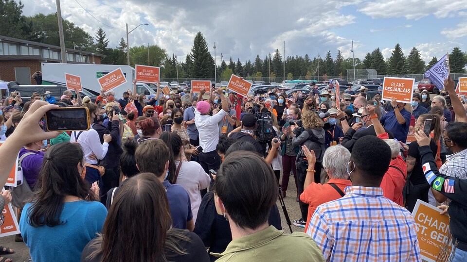 Une foule avec des pancartes du NPD acclame Jagmeet Singh qui lève les bras.