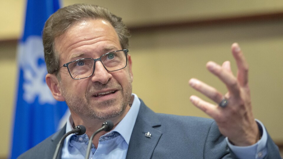 Le bras levé, Yves-François Blanchet s'adresse aux médias, regardant vers la gauche.