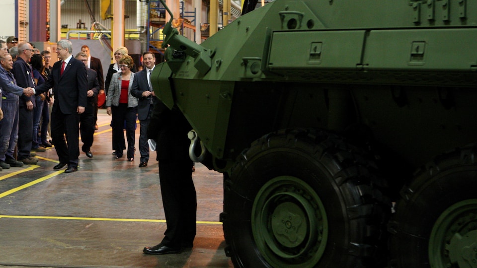 Le premier ministre de l'époque, Stephen Harper, visite l'usine de General Dynamics Land Systems. Un véhicule blindé est à l'avant-plan.