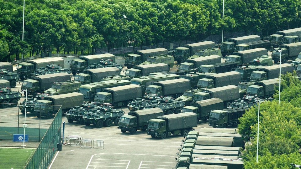 Des camions et des véhicules blindés de transport de troupes près du stade de Shenzhen Bay.