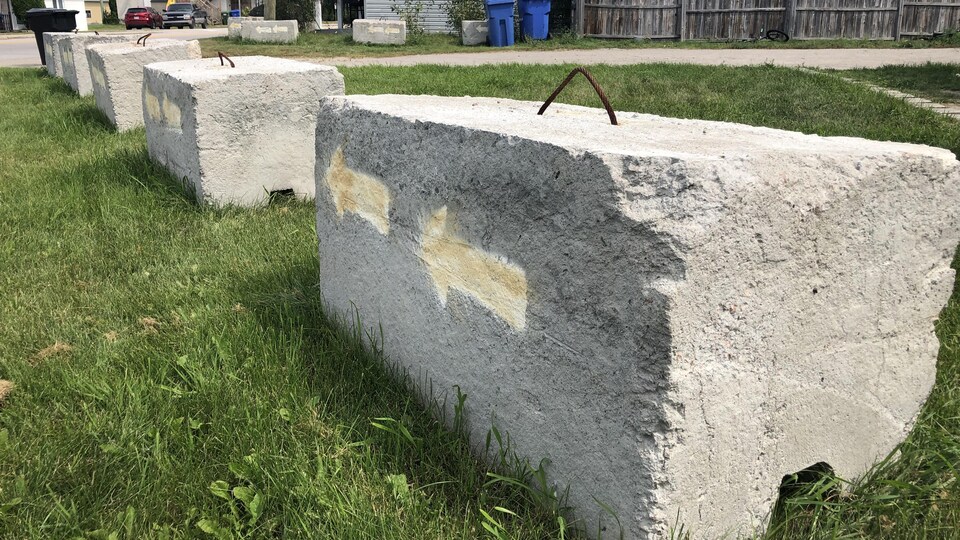 Des blocs de béton avec des flèches peinturées dessus sur un terrain devant une maison.